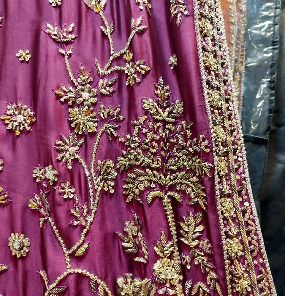 Close-up of magenta fabric with golden handmade floral embroidery