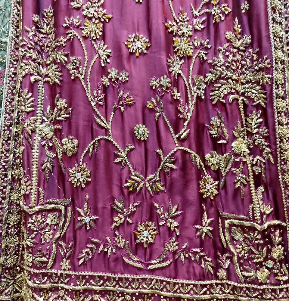 Close-up of pink dress border with dense golden embroidery